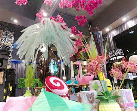 Blumen für Dich Gin – floraler Craft-Gin aus Deutschland mit Hibiskus, Holunder und Rosenblüte, handwerklich destilliert und perfekt für frische Gin & Tonics. „Deko-Arrangement im BSix® Conceptstore mit großem weißen Federbouquet, pinken Blüten und Geschenkartikeln auf einem Tisch.“