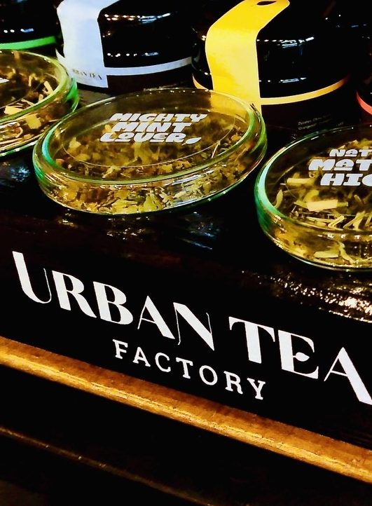 Urban Tea Factory® Teegläser mit losem Tee und Verpackungen auf Verkaufsdisplay