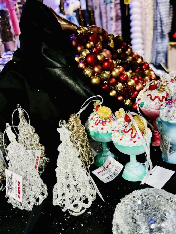„Weihnachtsanhänger & Deko – BSix® Conceptstore“ „Weihnachtliche Dekoanhänger und bunt verzierte Figuren auf schwarzer Präsentationsfläche im BSix® Conceptstore.“