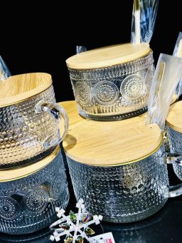 Elegante Glasdosen mit strukturierter Oberfläche & Holzdeckel Mehrere dekorative Glasbehälter mit geprägtem Muster und Holzdeckeln, arrangiert auf einer dunklen Fläche.